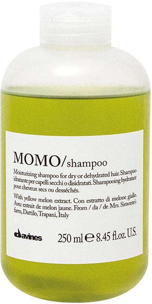 En grön flaska med MOMO-schampo för torrt eller skadat hår, med vit etikett och svart text.