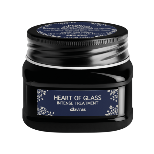 En svart burk med blå etikett som säger 'Heart of Glass Intense Treatment' av Davines, dekorerad med vita blommor.