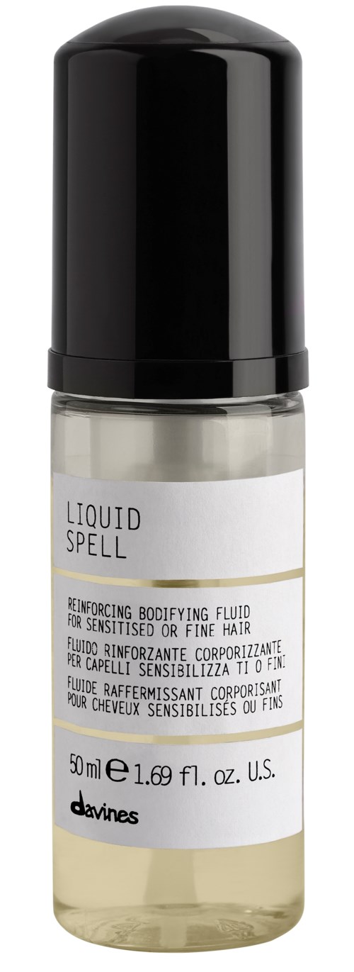 A small, transparent bottle with a black cap labeled 'Liquid Spell' for hair, with white and gold text.