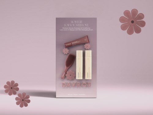 Ein Hautpflege-Geschenkset mit zwei Flaschen, einer Bürste und rosa Blumen auf rosa Hintergrund.