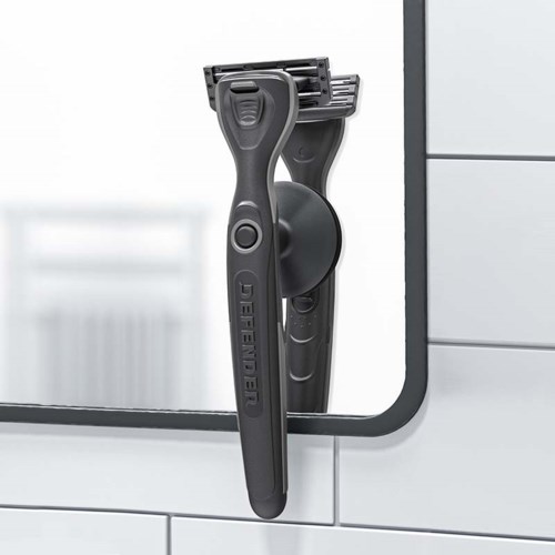A cleaning razor hanging on a mirror in a bathroom.