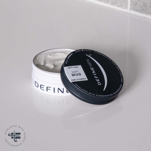 A black container with white cream and the words "SOFT MUD" and "DEFINE MEN" on the lid.