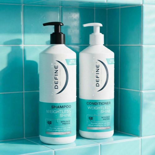 Two white bottles of shampoo and conditioner with black and white pumps sit on turquoise tiles. They are labeled for weightless shine.