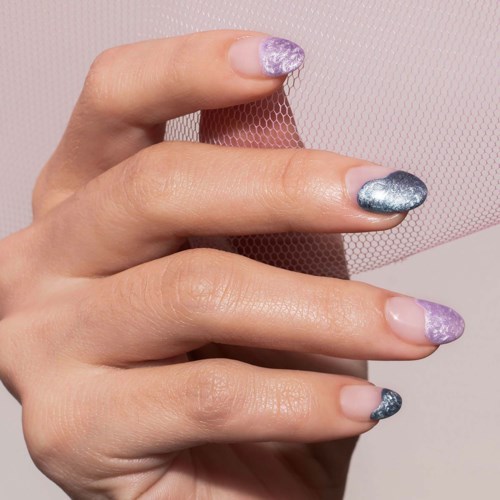 A hand with painted nails holds pink mesh fabric, with nails painted in purple and silver shades.