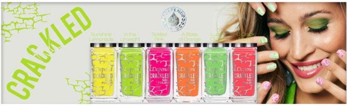 En kvinna med färgglad makeup ler, med nagellackflaskor märkta 'CRACKLED' framför sig.