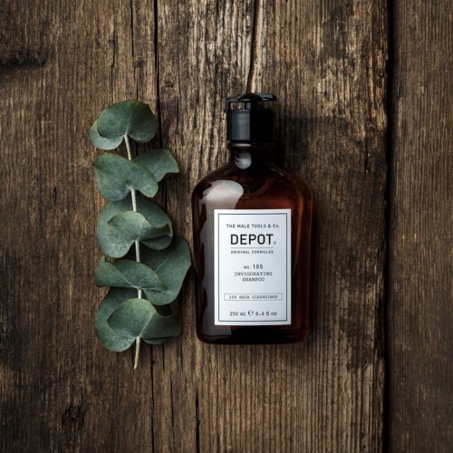Een bruin flesje shampoo met 'DEPOT' en een groene eucalyptustak naast een houten oppervlak.