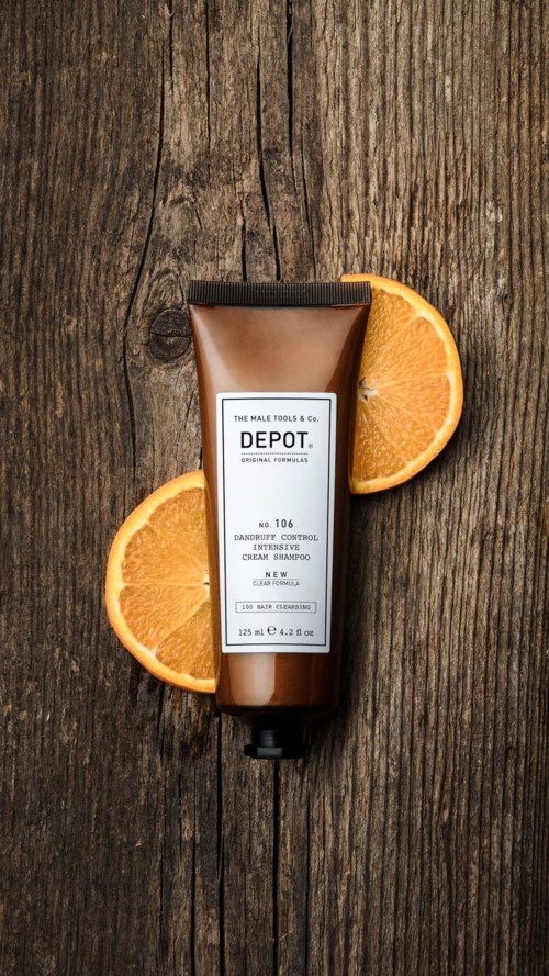A bottle of beard shampoo on wood with orange slices around it.