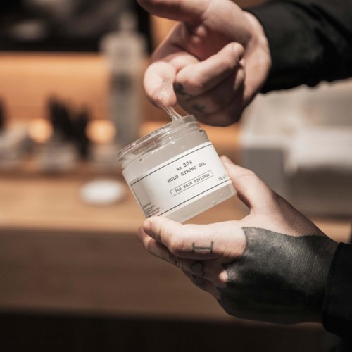 Someone is holding a jar of cream or lotion, with their other hand scooping out some product.