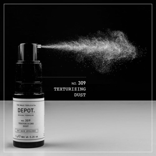 Een sprayfles met label 'Texturizing Dust' die fijne stofdeeltjes in de lucht spuit.