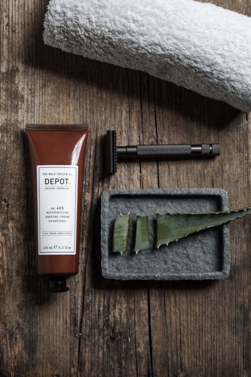 Shaving tools, a towel, and aloe vera gel on a wooden surface.