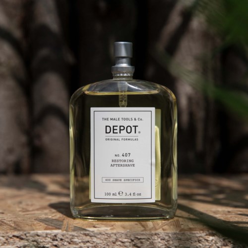 En tydlig glasflaska med en silverkork och en vit etikett, placerad utomhus på trä, innehåller aftershave.