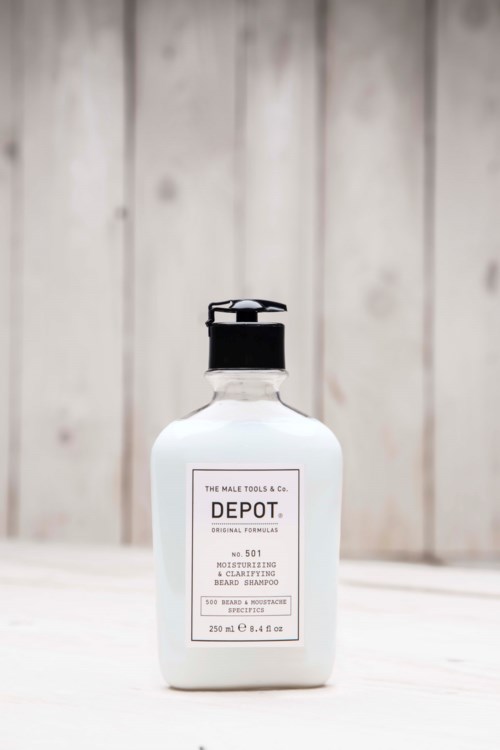 A white bottle with a black cap on a white surface against a wooden background.