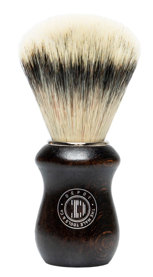 A shaving brush with a dark handle and light, fluffy bristles, set against a black background.