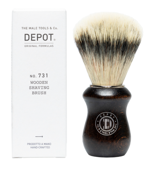 A wooden shaving brush with a dark handle and white bristles. The box is white with text and logo.