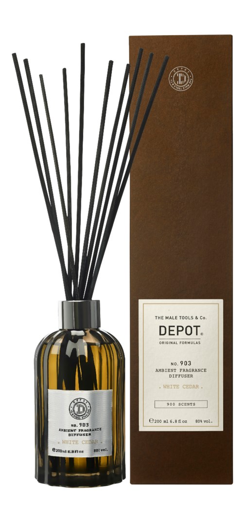 A brown glass bottle with black reeds and a label, next to a tall brown box, both are Depot fragrance products.