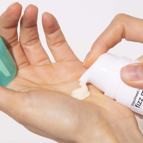 Jemand trägt Creme oder Lotion auf die Hand auf. Die Person drückt auf den Pumpknopf, um das Produkt zu erhalten.