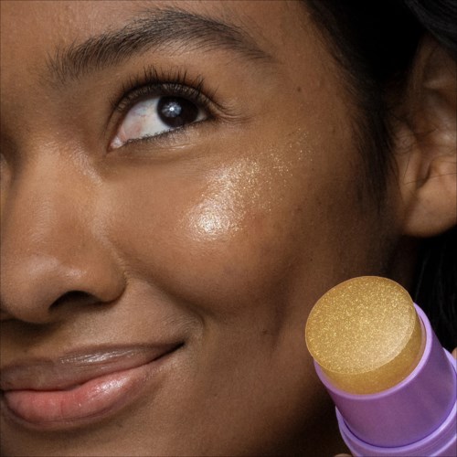 Close-up van een vrouw met glanzende huid en een schoonheids spons bij haar wang.