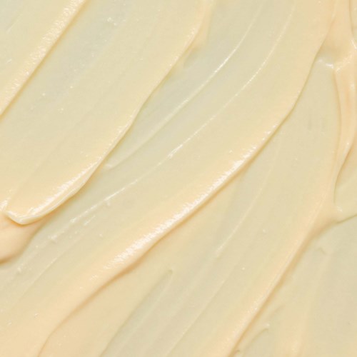 Cremefarbige Substanz gleichmäßig in diagonalen Linien verteilt. Sieht weich und reichhaltig aus, vielleicht Butter oder Zuckerguss.