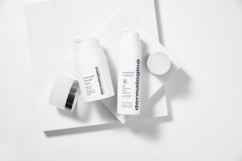 Twee flessen huidverzorgingsproducten met witte doppen op een witte oppervlakte, één gemerkt 'dermadiolabe' en 'powerful moisture.'