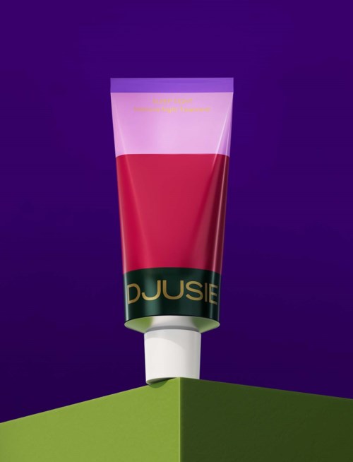 Eine Tube mit Kosmetikprodukt auf einer grünen Oberfläche vor lila Hintergrund.