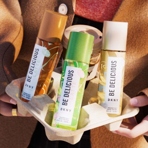 Drie DKNY Be Delicious parfumflesjes in verschillende kleuren op een dienblad. Mensen houden het dienblad, tonen de parfums.