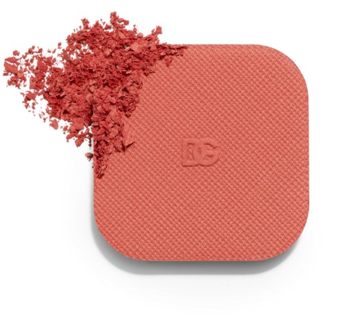 A square peach-colored blush with a textured surface, partially crushed, revealing loose powder.