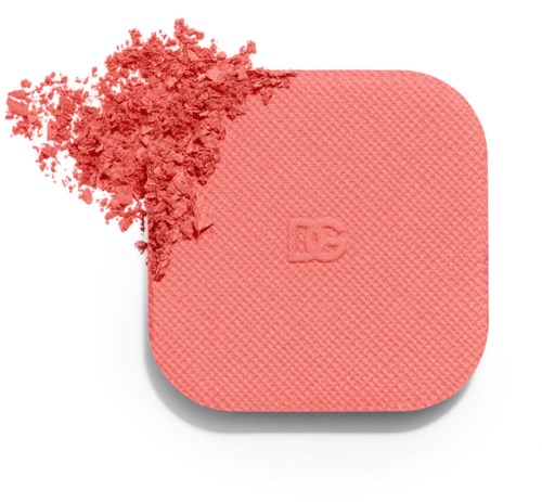 A pink square makeup sponge with a textured surface, appearing to be used with some broken powder or product.