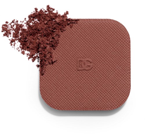 A round blush-colored makeup product with a textured surface and a small quantity spilled out.