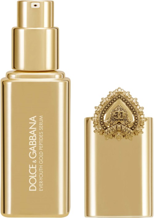 Guldfärgad flaska av Dolce & Gabbana hudvård med ett dekorativt lock och logga.