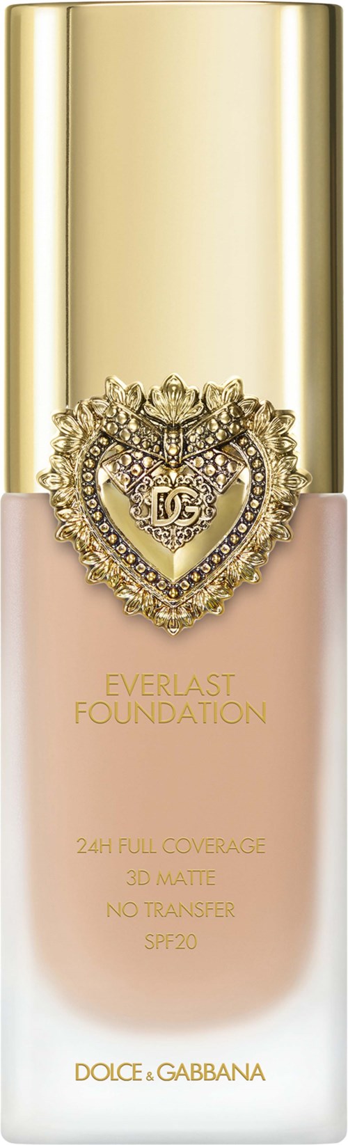 A foundation bottle with a gold cap, heart-shaped decoration with crystals, and pinkish-beige liquid inside.