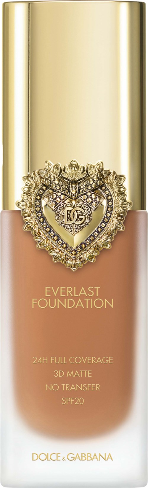 A foundation bottle with gold cap, heart-shaped jeweled logo, and beige-pink liquid.
