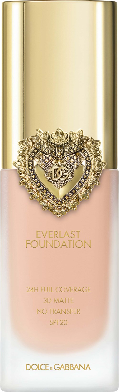 A foundation bottle with a gold cap, a pink and white body, and a heart-shaped decorative emblem on the front.