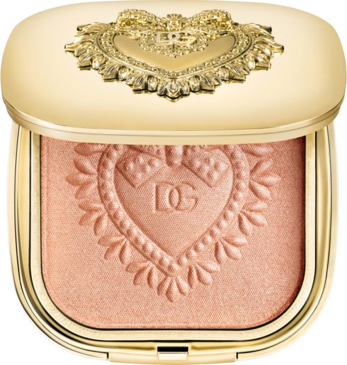 A compact with a gold top, decorated with a heart-shaped emblem and floral details, containing pink blush.