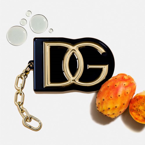 A Dolce & Gabbana logo keychain with orange prickly pears and a few water droplets on a white background.