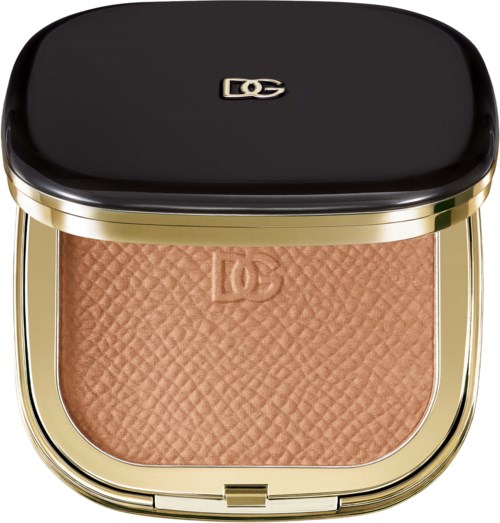 A makeup compact with a golden frame and a black lid, containing a brown pressed powder with embossed logo.