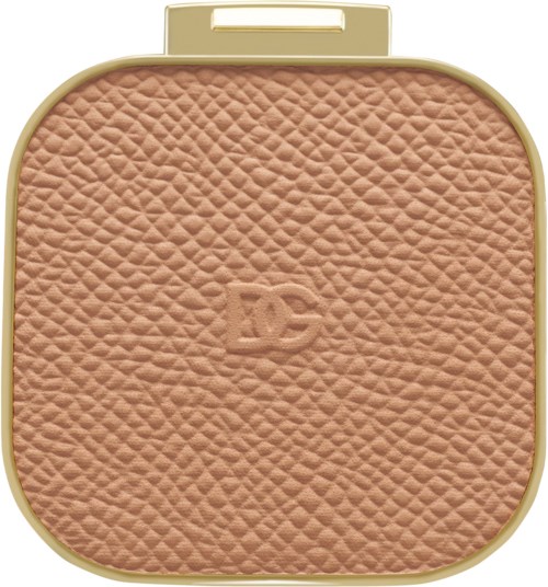 Komprimert pudder med teksturert beige overflate og gullfarge.