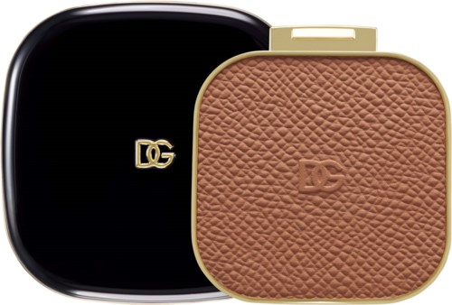 En kompakt med svart deksel og gulllogo, åpen for å vise teksturert ferskenfarget pudder eller blush.