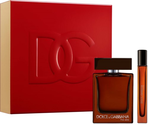 A perfume bottle with a black cap and a clear, tall, orange-colored vial beside it, all in front of a red and beige gift box.
