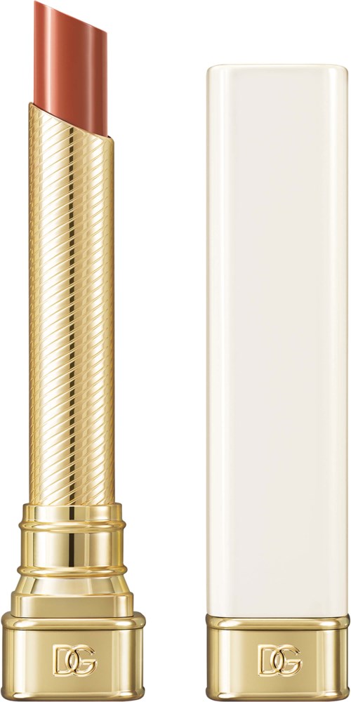 A gold lipstick tube with a white cap, partly opened, showing red lipstick. Plain black background.