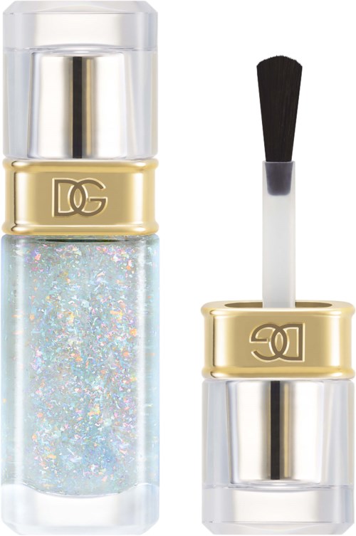 A clear nail polish bottle with sparkly glitter, a gold band with DG logo, and a separate applicator with a black tip.