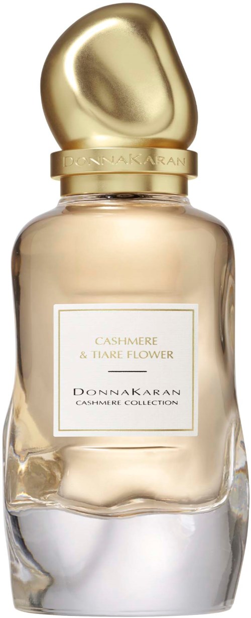 Een parfumfles met een glanzende, gouden dop en een zachte gekleurde vloeistof, gelabeld 'Cashmere & Tiaré Flower'.