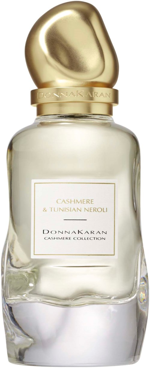 Een parfumfles met een gouden, ronde dop en een heldere, onregelmatige glasbus. Het label toont 'Cashmere & Tunisian Neroli.'
