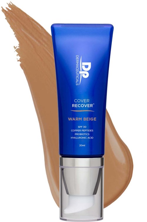 A blue tube of skincare product with white text, placed in front of a beige foundation smear.