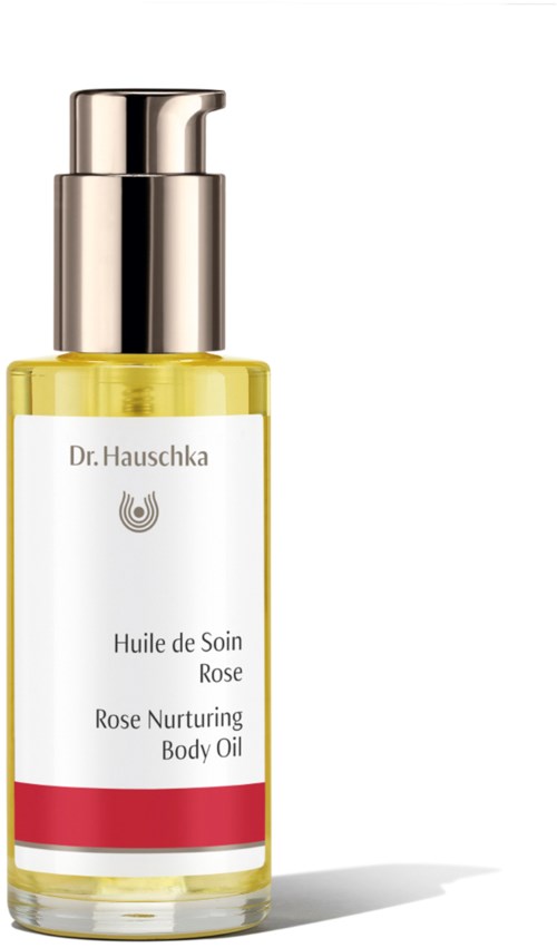 En liten gul flaske med sølvfarget hette inneholder rosepleiende body oil. Den har en hvit etikett med røde detaljer.