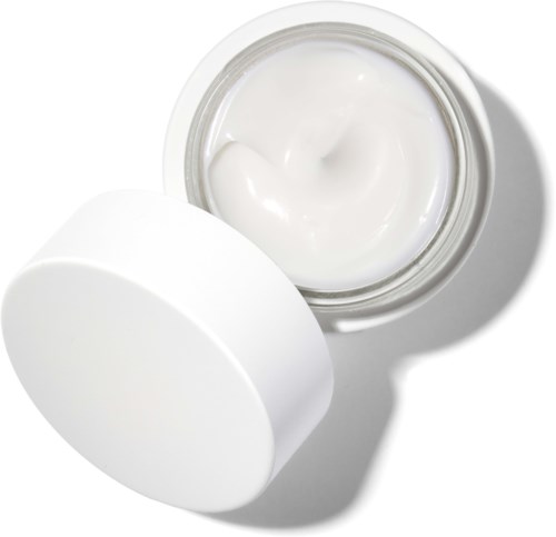 Weiße Creme in einem offenen Behälter mit Deckel daneben. Die Creme ist glatt und leicht glänzend.