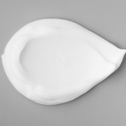 Witte crème of lotion in een druppelvorm op een grijze achtergrond.
