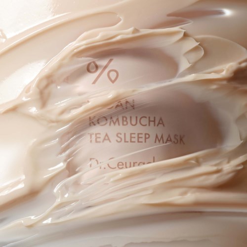 Een roomkleurig product met tekst die 'KOMBUCHA TEA SLEEP MASK' zegt, gedeeltelijk bedekt door het product.