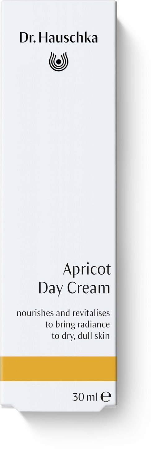 Ein langer weißer Karton mit schwarzem Text, zeigt den Produktnamen „Apricot Day Cream“ und eine Beschreibung, mit kleinem Logo.