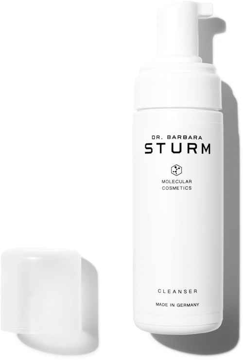 En hvit flaske med Dr. Barbara Sturm hudpleieprodukt med pumpe og en liten hvit beholder i nærheten.