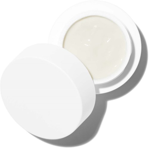 Ein kleiner, runder, weißer Behälter offen mit Creme oder Lotion darin, Deckel in der Nähe.